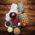 Glenwood meat sticks with pineapple, soy, brown sugar, onion, and spices on a rustic wooden board.