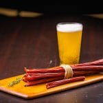Glenwood meat sticks bundle on wooden board with a pint of beer, pub-style snack presentation.